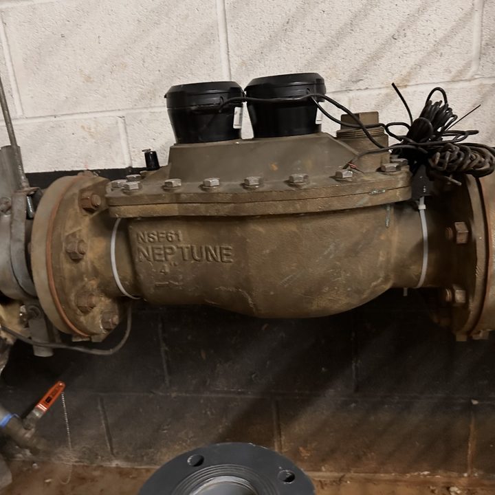 A large 4-inch commercial water meter on a building's main water line.