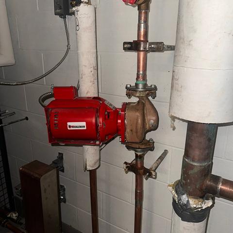 A red circulator pump connected to copper piping.