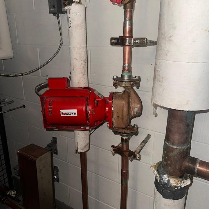 A red circulator pump connected to copper piping.